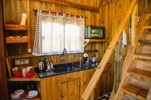 a kitchen with a sink and a window in a cabin at Chalé Rústico com Hidromassagem e Piscina in Imaruí