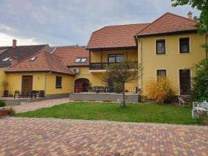 a large yellow house with a brick driveway at Diófa Vendégház in Eger