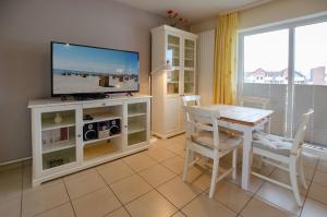 ein Wohnzimmer mit Fernseher und Tisch und Stühlen in der Unterkunft Seerose Koki in Kellenhusen