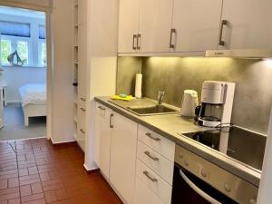 a kitchen with white cabinets and a sink at Amselnest in Wyk auf Föhr