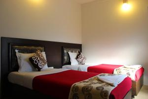 a bedroom with two beds with red and white at Mount Residency in Chennai