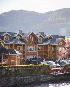 a large house with cars parked in front of it at Apart Presidencial ROTUI in San Martín de los Andes
