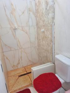 a bathroom with a shower and a toilet with a red rug at Quarto casal ventilador in Conde