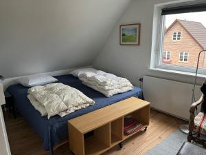 1 dormitorio con 1 cama con 2 almohadas y mesa en Annes overnatning, en Svendborg