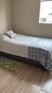 a bed in a bedroom with a rug and a window at Arriendo apartamento diario in Puerto Montt
