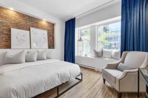 une chambre avec un lit blanc et un mur de briques dans l'établissement Initial / Suite trésor / Centre-Ville de Québec, à Québec