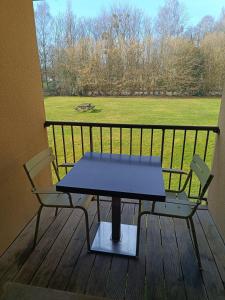 a table and chairs on a balcony with a view of a field at Studio les Hauts de Honfleur in Équemauville