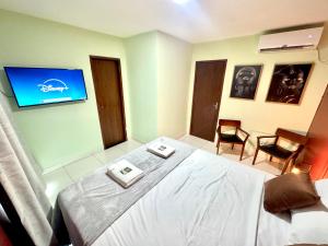 a bedroom with a bed and a tv on the wall at Studio Charmoso e Aconchegante em Itaberaba II in Itaberaba
