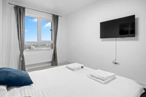 a bedroom with a bed with a tv on the wall at Minimalist Green & Grey Flat in Bucharest