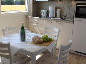 a white table with a plate of food and a bottle of wine at Haus Wildfang FeWo 2 in Dahme