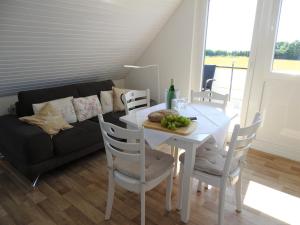 a dining room with a white table and a couch at Haus Wildfang FeWo 2 in Dahme