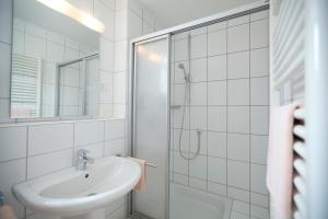 a white bathroom with a sink and a shower at Hotel Möhringer Hof in Stuttgart