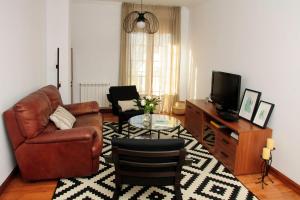a living room with a leather couch and a television at Silleda Via da Plata in Silleda