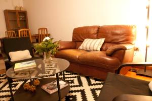 a living room with a brown leather couch and a table at Silleda Via da Plata in Silleda