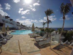 a swimming pool with lounge chairs and palm trees at Lago Verde Suite 25 in Puerto del Carmen