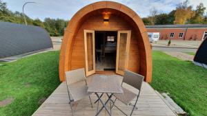 a small wooden house with two chairs in a yard at 03 Premium Camping Pod "Nordstrandischmoor" in Silberstedt
