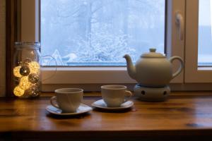 two cups and a teapot on a table next to a window at Hof Timmermann - Spatzennest in Ottenstein