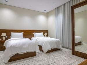 a bedroom with two beds and a large mirror at أزهار طيبة in Al Madinah