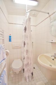 Un baño con inodoro y cortina de ducha. en Ferienbungalow 3, en Dahme 1 foto más