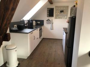 a kitchen with white cabinets and a black refrigerator at FeWo Apartment Maria in Kürten