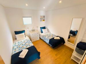 a bedroom with two beds and a mirror at Herama Sea Guesthouse in Vila Nova de Gaia