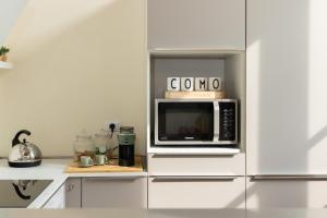 una cocina con microondas sobre armarios blancos en Apartment in the old town of Como - MonicaComoApartment, en Como
