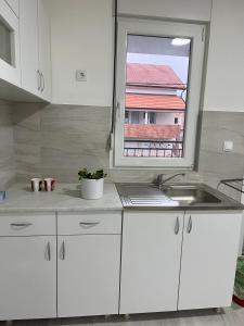 a white kitchen with a sink and a window at Airport Art Villa in Čukarica