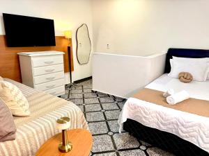 a hotel room with two beds and a flat screen tv at AirComfort Stay - 15min Aeroporto Internacional de Guarulhos in Guarulhos +24 photos