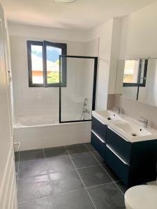 a bathroom with two sinks and a tub and a toilet at 5mn Crolles Chambre au calme parking gratuit - belle cuisine partagée in Froges