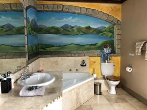 a bathroom with a tub and a toilet and a painting at Listening Wind Self-Catering accommodation in Bettyʼs Bay