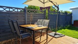 a table and chairs with an umbrella on a deck at Ferienhaus Boje14a in Haffkrug +5 photos