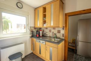 a kitchen with wooden cabinets and a sink and a window at Ferienhaus Zum Waldrand in Erfweiler