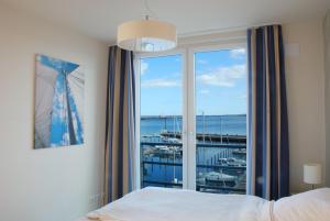 a bedroom with a large window with a view of a marina at Apartment 24, Pier 24, Blickrichtung offene SeeBinnenhafen Nord in Eckernförde +17 photos