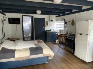 a bedroom with a bed and a kitchen with a refrigerator at Hostel Cala 816 in Frutillar