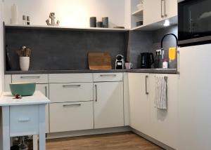 una cocina con armarios blancos y un tazón verde en una encimera en Kellenhusen Tor Ankerplatz, en Kellenhusen 17 fotos más