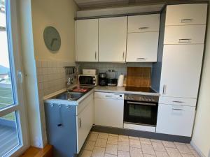 a small kitchen with white cabinets and a sink at Haus AchternDiek Strandhafer in Dahme
