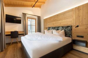 a bedroom with a large white bed and a desk at Kreuzspitze Appartement Zillertal FUZ103 in Fügen
