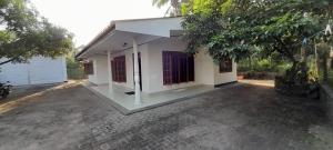 HomagamaVistar house的一座白色的小建筑,有红色的门