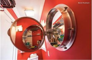 two mirrors on a red wall in a bathroom at Boat House Loft in Port Rexton