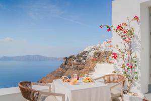 a table with a plate of food and a view of the ocean at Spitia Tzitzi in Imerovigli