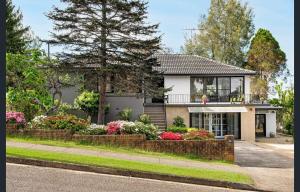 a house with a balcony and flowers in front of it at Spacious 5 Bedroom 3 Bath Three Sisters Getaway in Katoomba