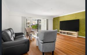 a living room with a couch chair and a television at Spacious 5 Bedroom 3 Bath Three Sisters Getaway in Katoomba