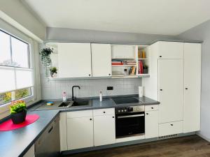 a kitchen with white cabinets and a sink at Fewo Elke in Barsinghausen