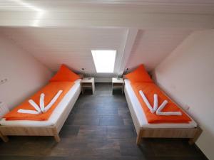 two beds in a attic with orange and white pillows at Ferienwohnung 11 in Ochsenhausen