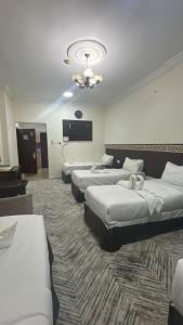 a hotel room with three beds and a chandelier at فندق ارجوان الصفوة in Miná
