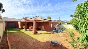 a brick house with a yard with a ladder at Cozy comfortable House in Mildura