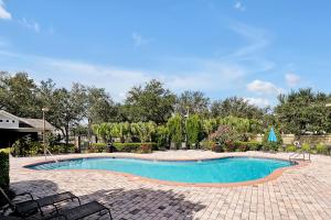 a swimming pool in a yard with chairs and trees at 11326 CYPRESS TRAIL DRIVE ORLANDO 3BED in Orlando