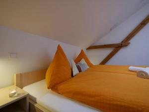 a bedroom with a bed with orange sheets and pillows at Ferienwohnung 6 in Ochsenhausen
