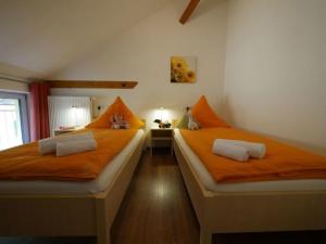 two beds in a room with orange pillows at Ferienwohnung 6 in Ochsenhausen