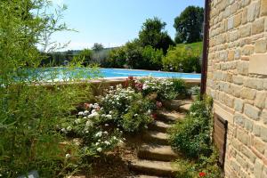 a garden with flowers and a swimming pool at Casale di Gualdo in Gualdo di Macerata
